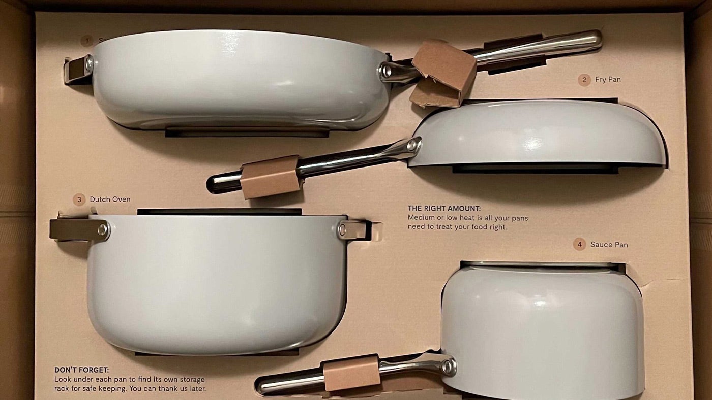Caraway white ceramic cookware set featuring a dutch oven, sauté pan, fry pan, and sauce pan in its packaging